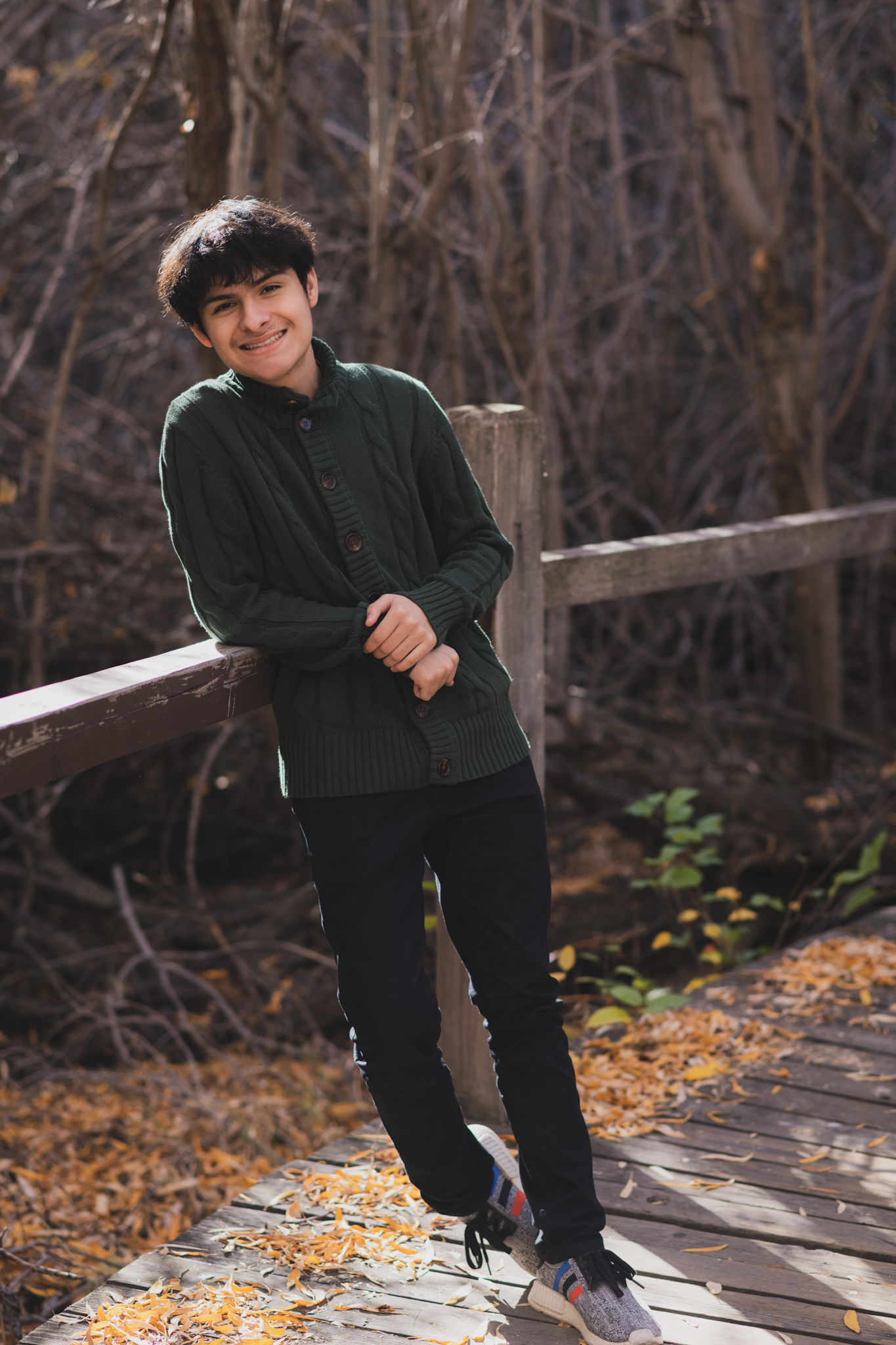 dark and moody portraits of a family in the forest mountains of Wrightwood california. The family is dressed in formal clothes and posing for the camera of the high deserts #1 best family photographer. The mother and daughter are wearing matching green velvet dresses and smiling. The father and son are wearing green sweatshirts. The San Bernardino mountain trees are the backdrop of this family photoshoot in the inland empire