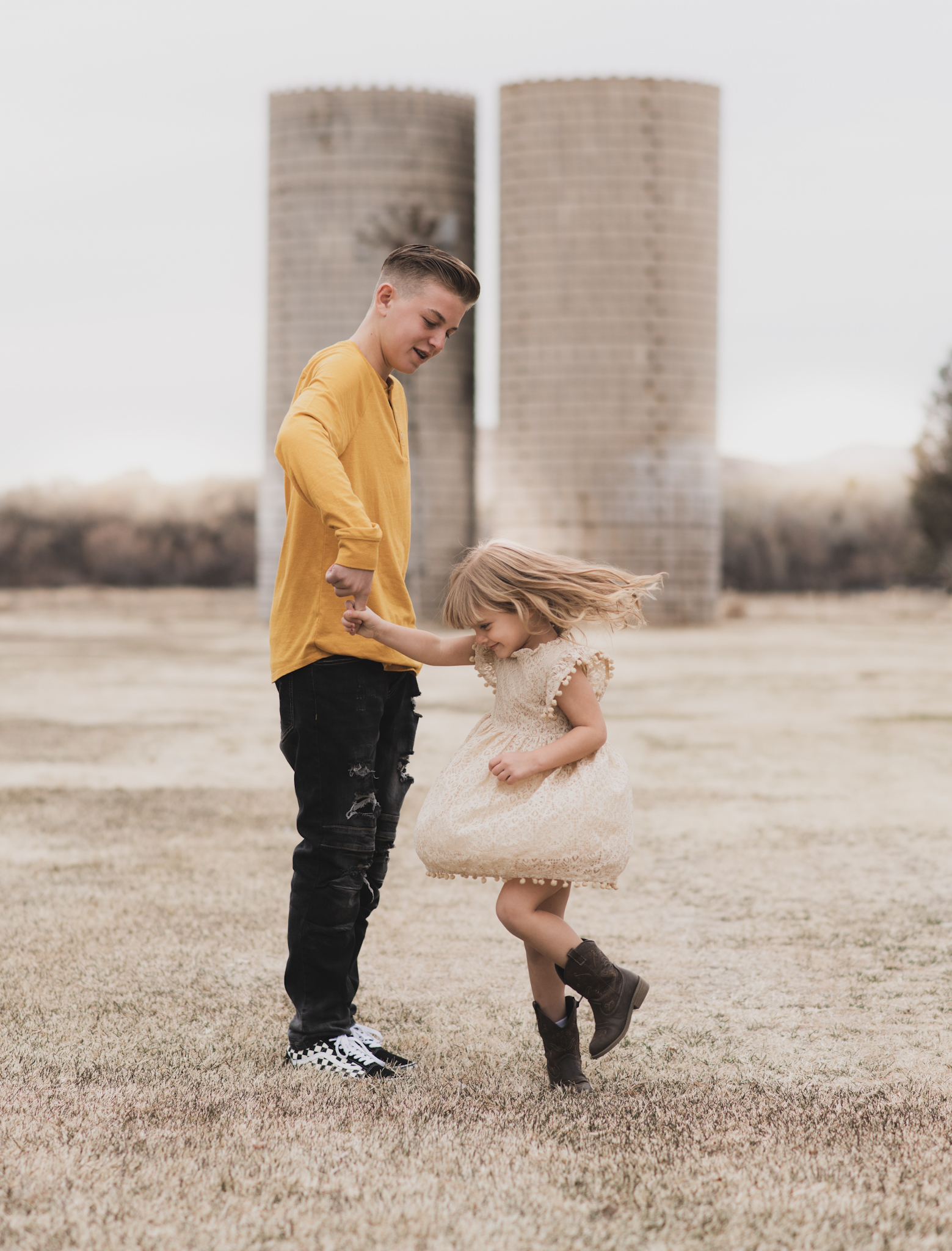 Light and airy portrait of a family posing for the high deserts best photographer at the Mojave narrows national park in Victorville California. They are dressed in formal clothing in front of giant water towers and smiling for the camera