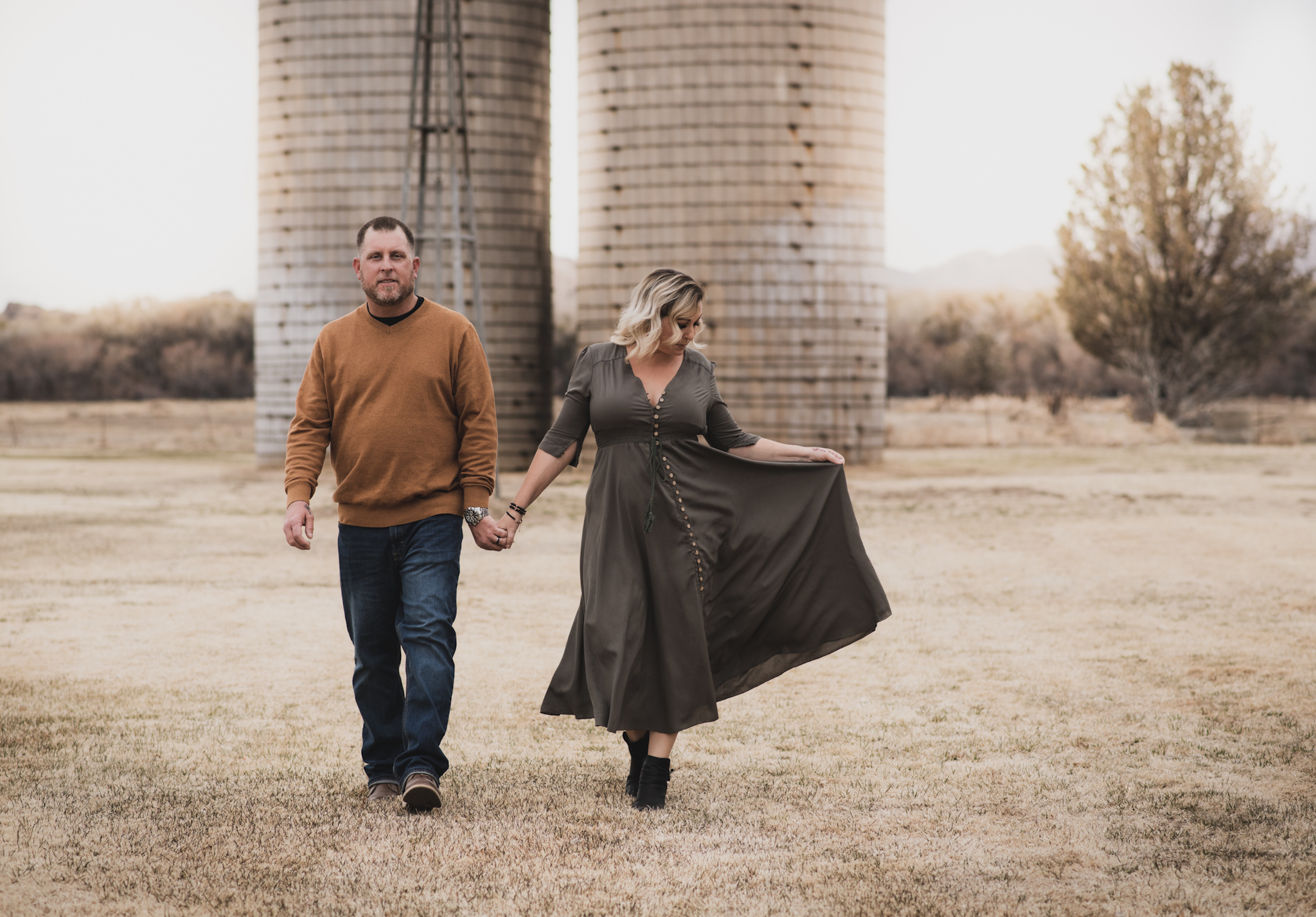 Light and airy portrait of a family posing for the high deserts best photographer at the Mojave narrows national park in Victorville California. They are dressed in formal clothing in front of giant water towers and smiling for the camera
