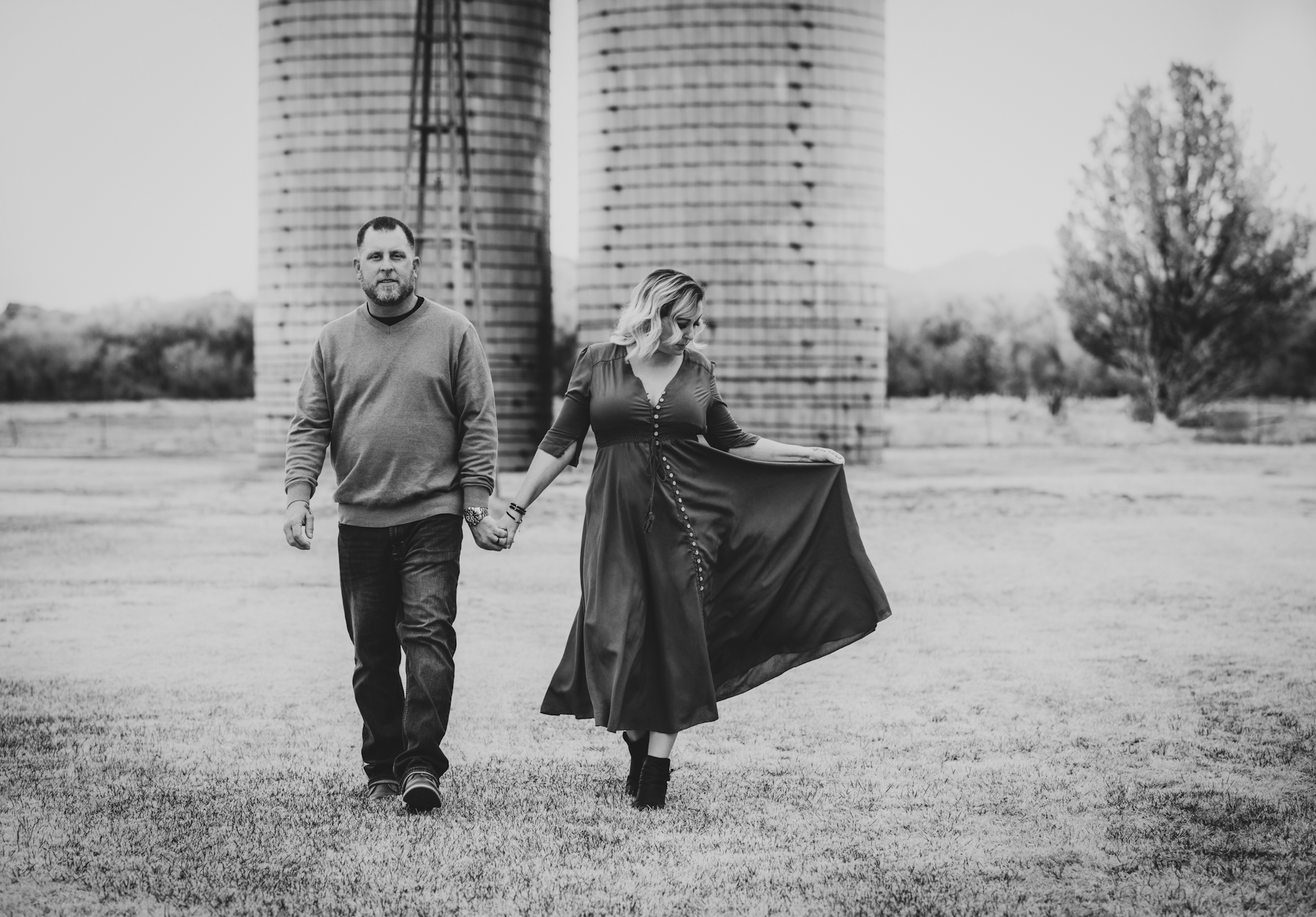 Light and airy portrait of a family posing for the high deserts best photographer at the Mojave narrows national park in Victorville California. They are dressed in formal clothing in front of giant water towers and smiling for the camera