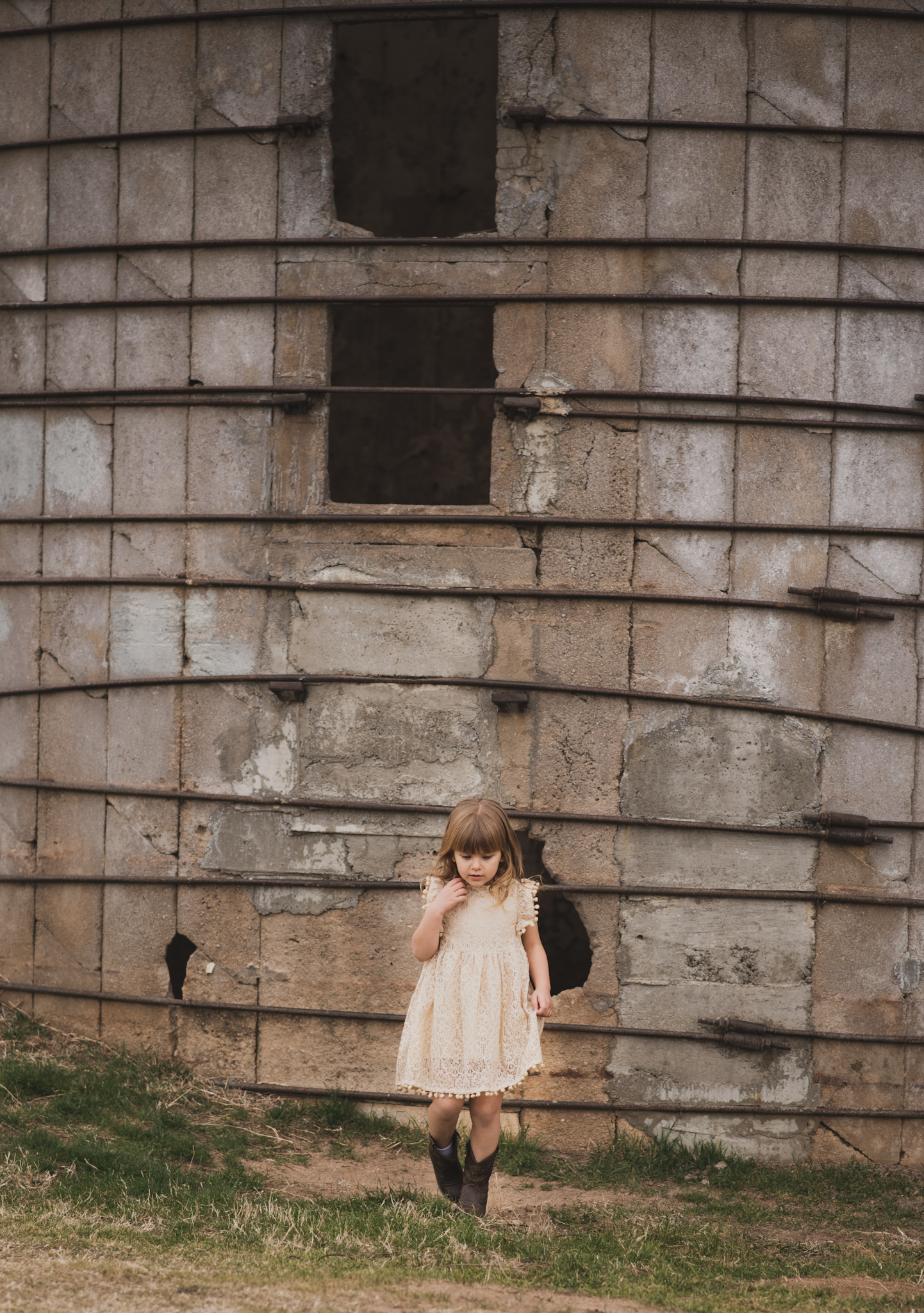 Light and airy portrait of a family posing for the high deserts best photographer at the Mojave narrows national park in Victorville California. They are dressed in formal clothing in front of giant water towers and smiling for the camera