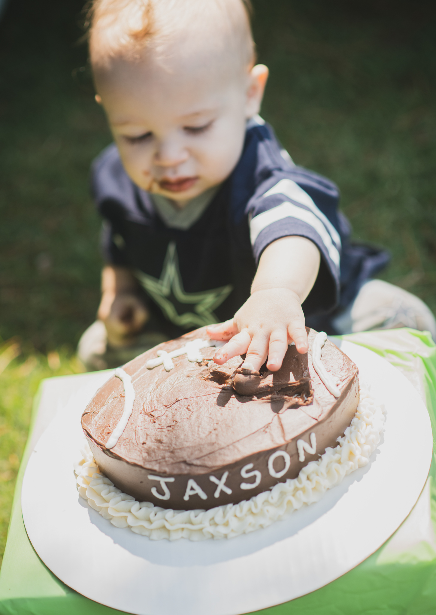 Light and airy portrait of a baby’s first birthday cake smash photoshoot shot in lake los angeles california in los angeles county. baby boy is smashing cake between his fingers and smiling at the camera of the high deserts best family photographer