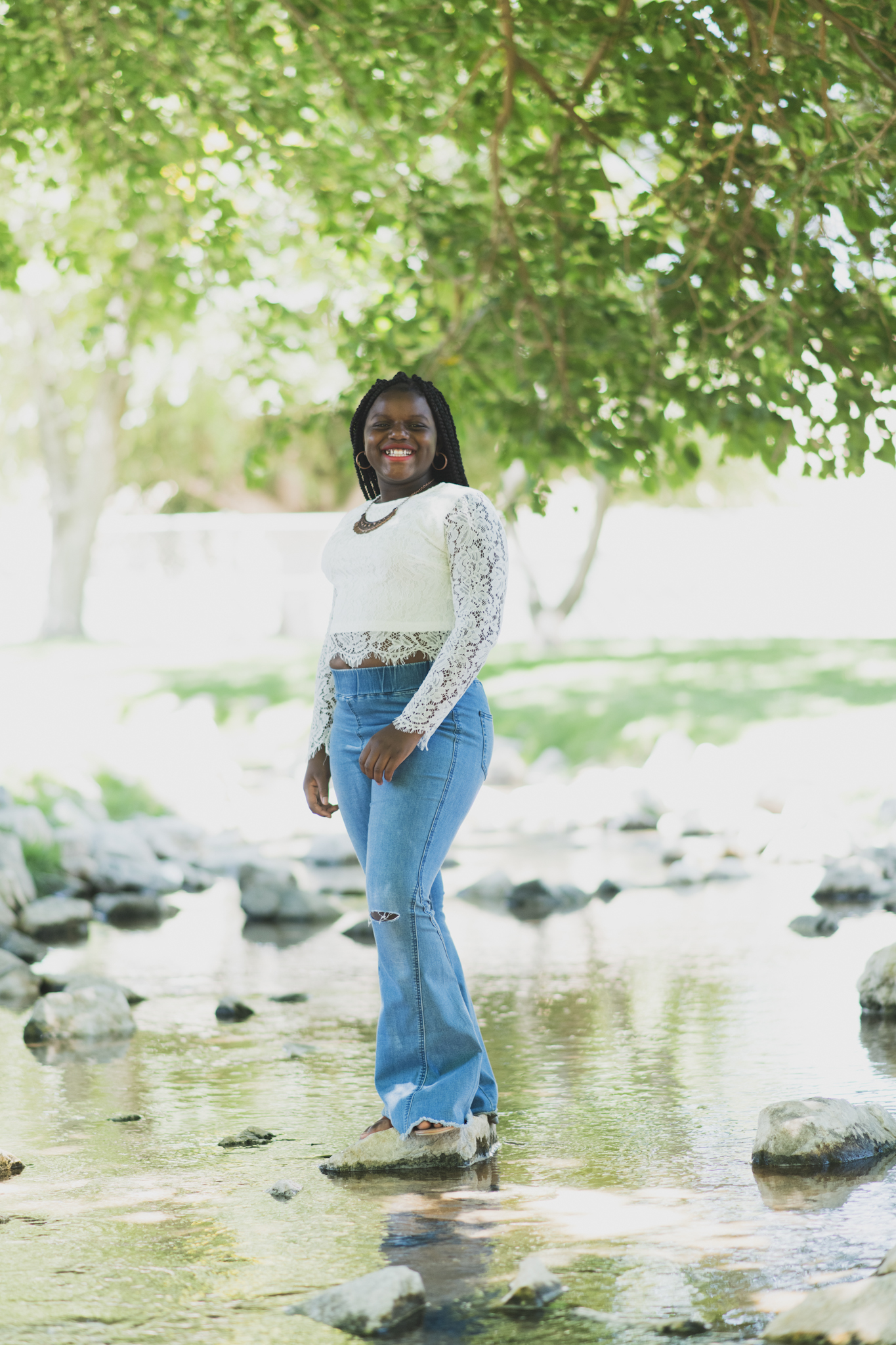 Light and airy family photoshoot at Hesperia Lake Park in the Inland empire. A Large family smiles and laughs for the high deserts best photographer. The scenery is green with lots of beautiful trees and nature. There is a pond in the background of these family portraits in the inland empire