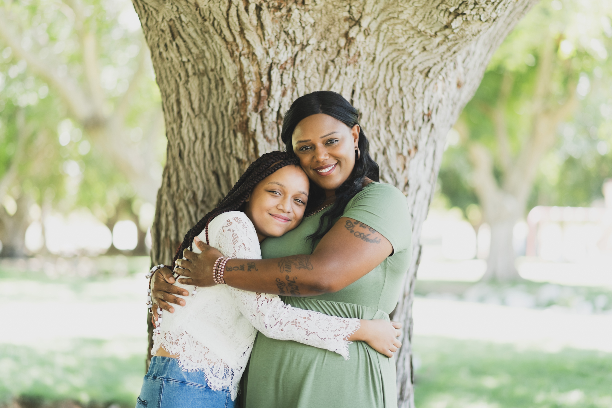 Light and airy family photoshoot at Hesperia Lake Park in the Inland empire. A Large family smiles and laughs for the high deserts best photographer. The scenery is green with lots of beautiful trees and nature. There is a pond in the background of these family portraits in the inland empire