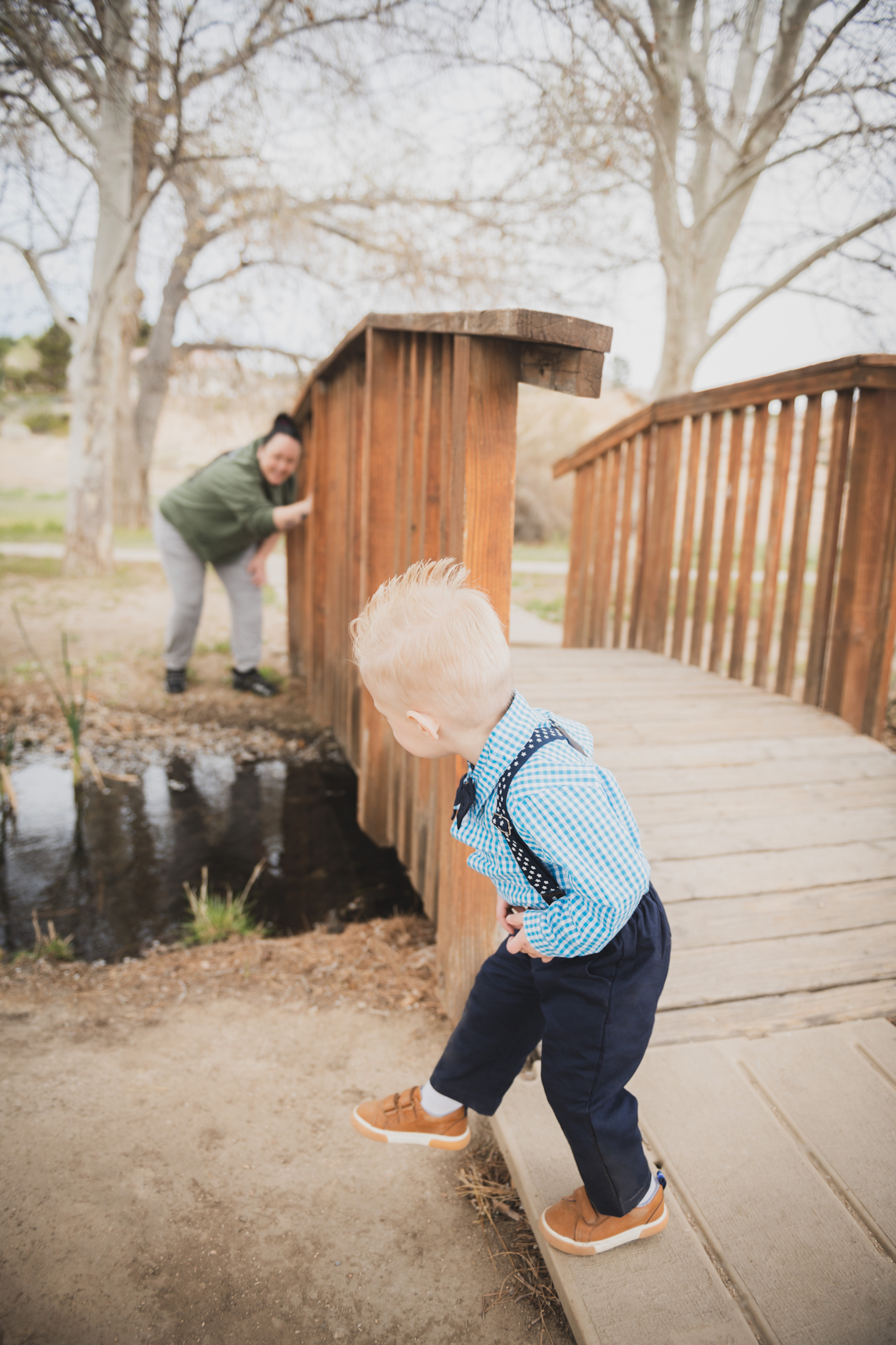 Light and air pictures of a three year old blonde boy playing in the grass at Hesperia Lakes park in Hesperia California in the High desert mountains. Little boy is playing with bubbles and laughing while wearing a blue bow tie and suspenders