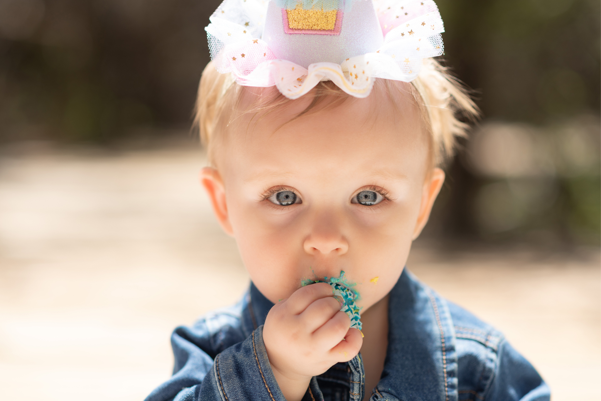 Light and airy pictures of a baby girl sitting on a magical bridge in the mountains of Wrightwood California. Baby is smashing a colorful cake and smearing it on her face in these high desert portraits