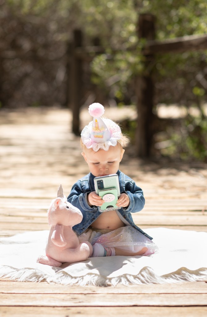 Light and airy pictures of a baby girl sitting on a magical bridge in the mountains of Wrightwood California. Baby is smashing a colorful cake and smearing it on her face in these high desert portraits