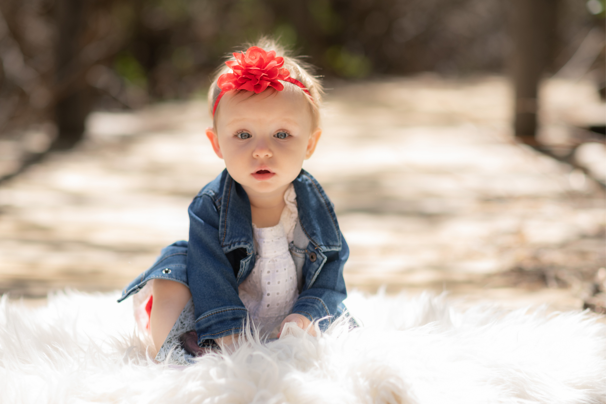 Light and airy pictures of a baby girl sitting on a magical bridge in the mountains of Wrightwood California. Baby is smashing a colorful cake and smearing it on her face in these high desert portraits