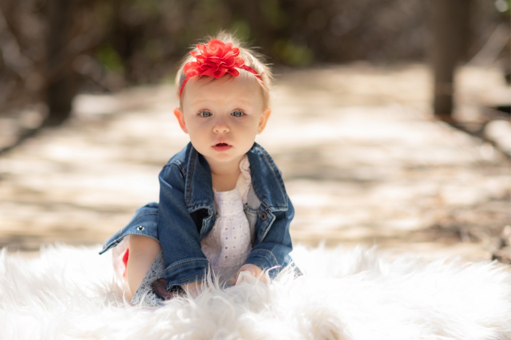 Light and airy pictures of a baby girl sitting on a magical bridge in the mountains of Wrightwood California. Baby is smashing a colorful cake and smearing it on her face in these high desert portraits