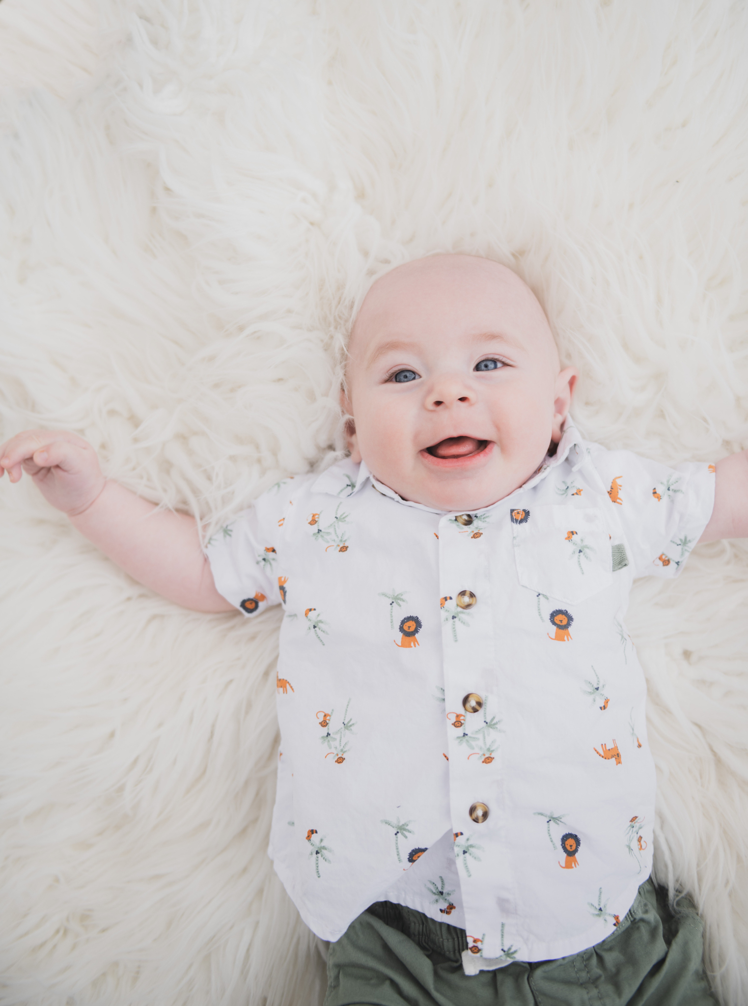 Light and airy pictures of a couple with a baby boy. Couple is wearing blue holding baby boy and smiling in these high desert portraits shot in the beautiful Hesperia Lakes park in the inland empire. There is a tree with white flowers blooming in the background