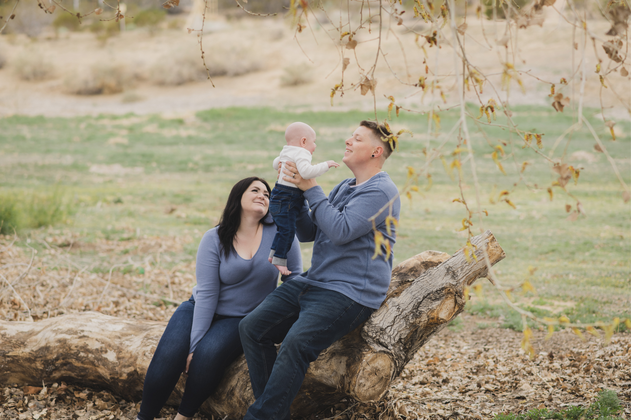 Light and airy pictures of a couple with a baby boy. Couple is wearing blue holding baby boy and smiling in these high desert portraits shot in the beautiful Hesperia Lakes park in the inland empire
