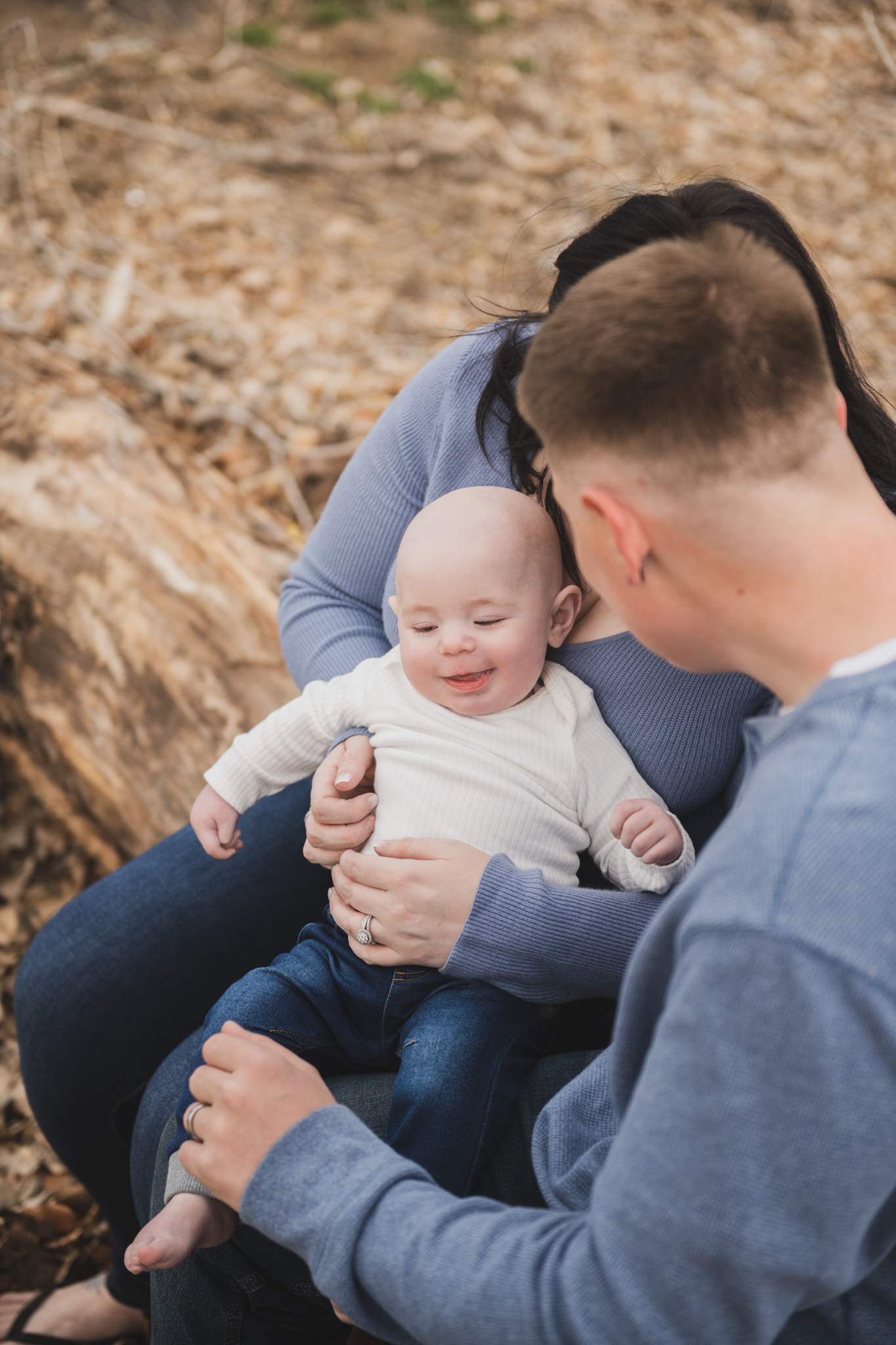 Light and airy pictures of a couple with a baby boy. Couple is wearing blue holding baby boy and smiling in these high desert portraits shot in the beautiful Hesperia Lakes park in the inland empire