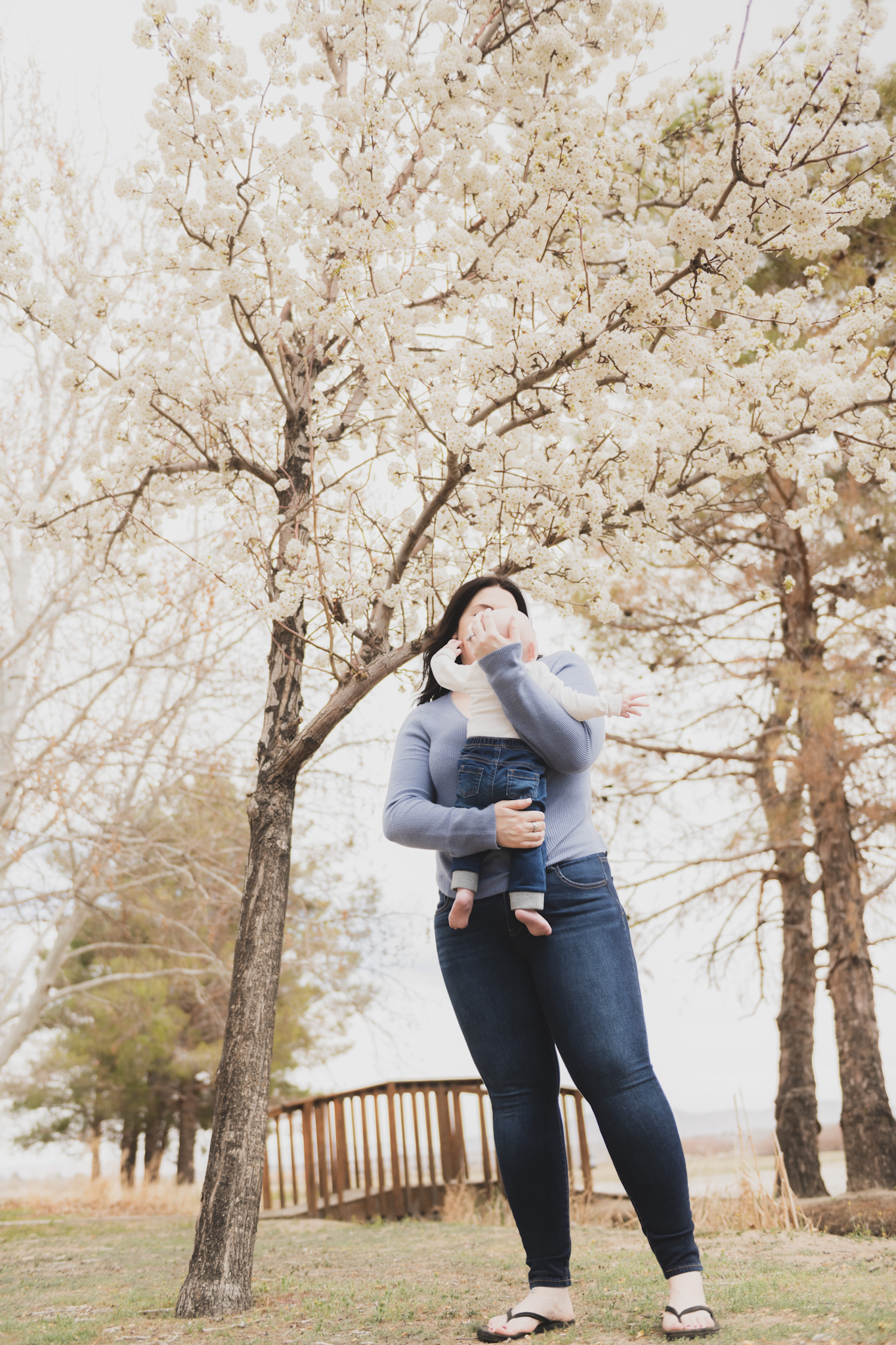 Light and airy pictures of a couple with a baby boy. Couple is wearing blue holding baby boy and smiling in these high desert portraits shot in the beautiful Hesperia Lakes park in the inland empire