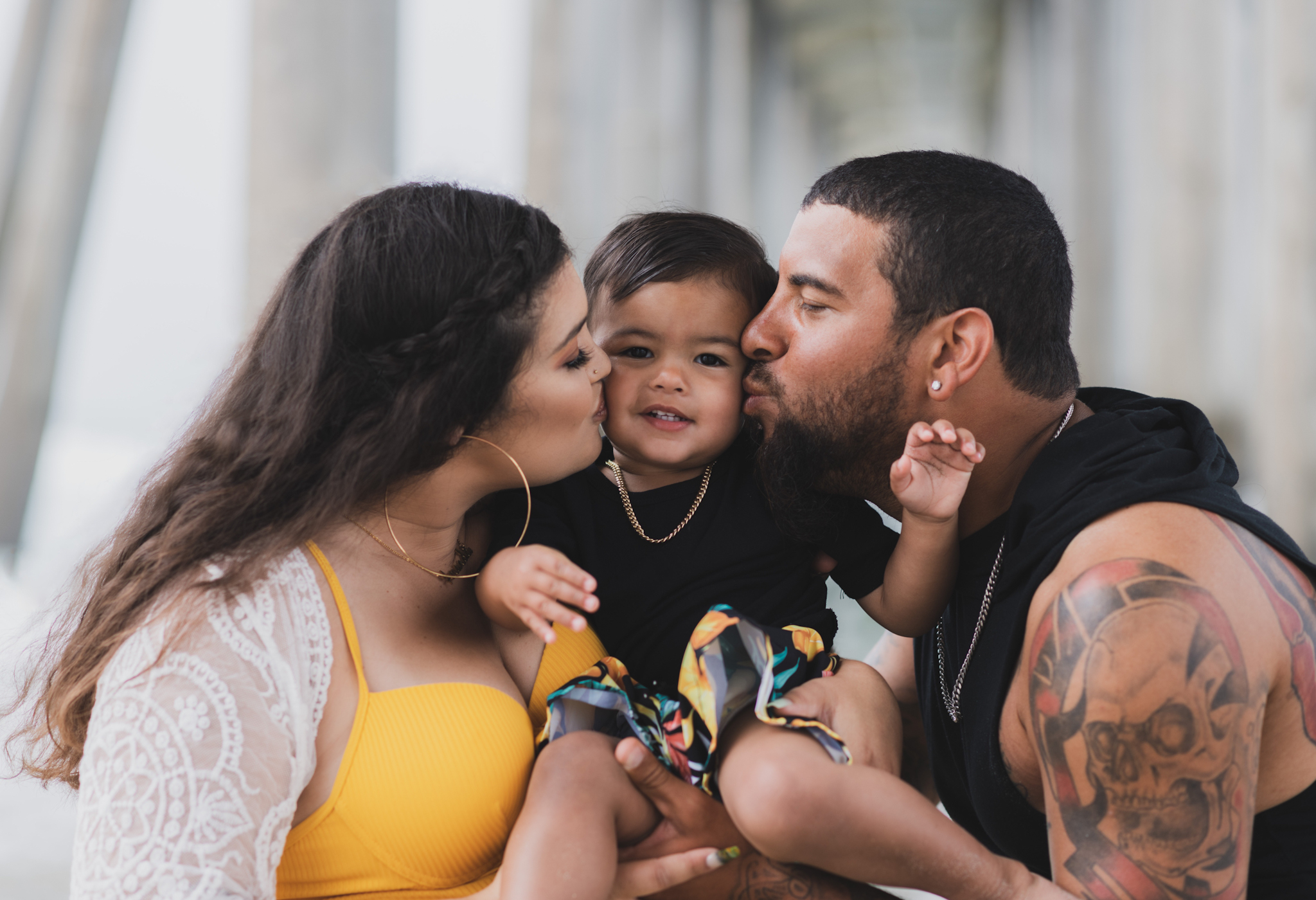 Light and airy portraits of a maternity shoot with family. Pregnant mother is wearing a bright yellow bathing suite in these Huntington Beach pictures. You can see blue waves in the background, the pier and husband and baby boy smiling with mother. Inland empire photoshoot at the beach