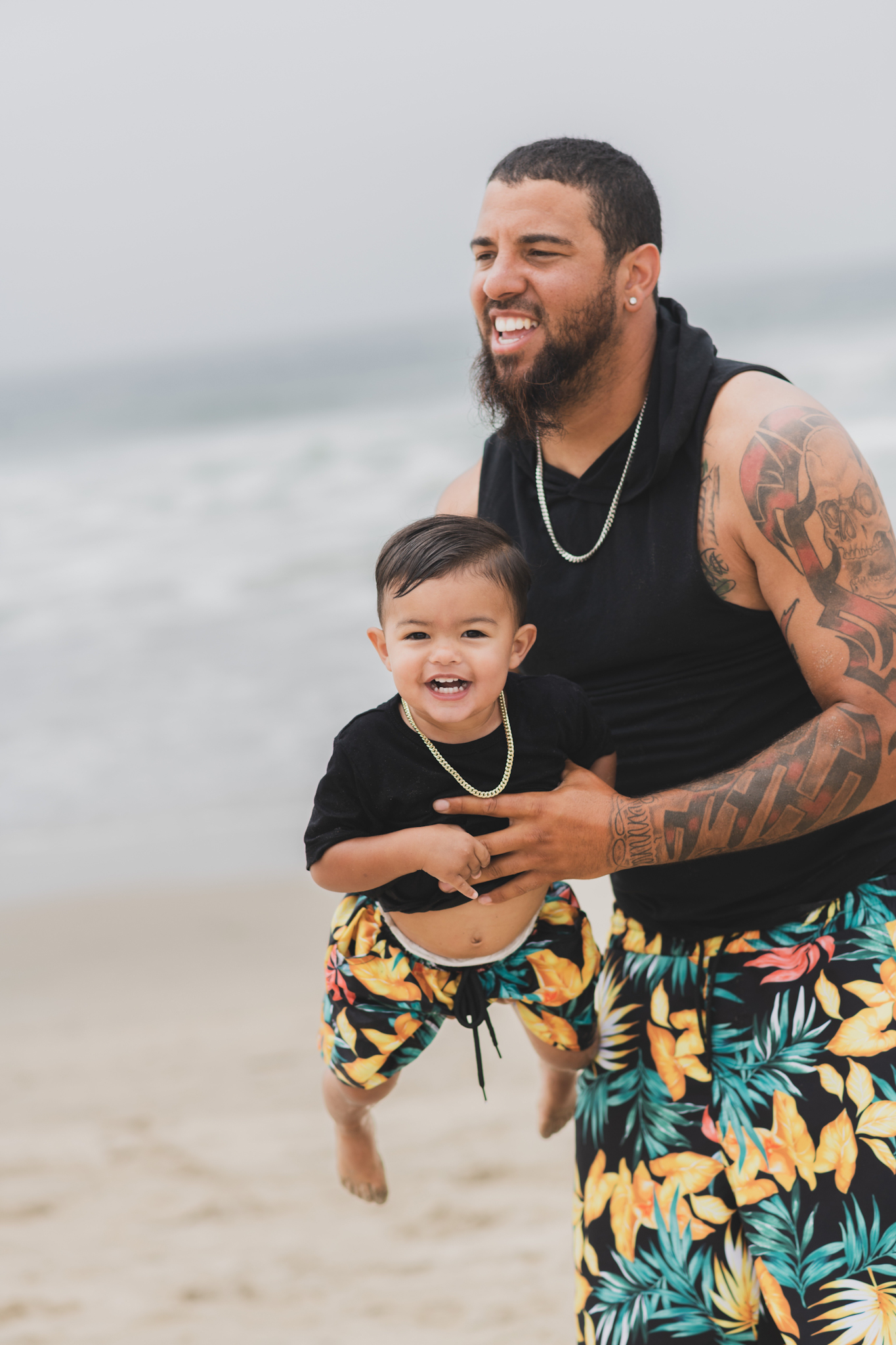 Light and airy portraits of a maternity shoot with family. Pregnant mother is wearing a bright yellow bathing suite in these Huntington Beach pictures. You can see blue waves in the background, the pier and husband and baby boy smiling with mother. Inland empire photoshoot at the beach
